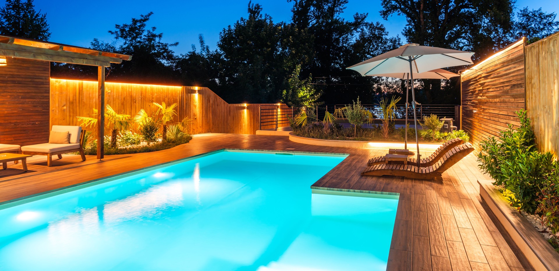 Modern pool with illuminated seating area at night. Concept of luxurious evening relaxation and outdoor ambiance